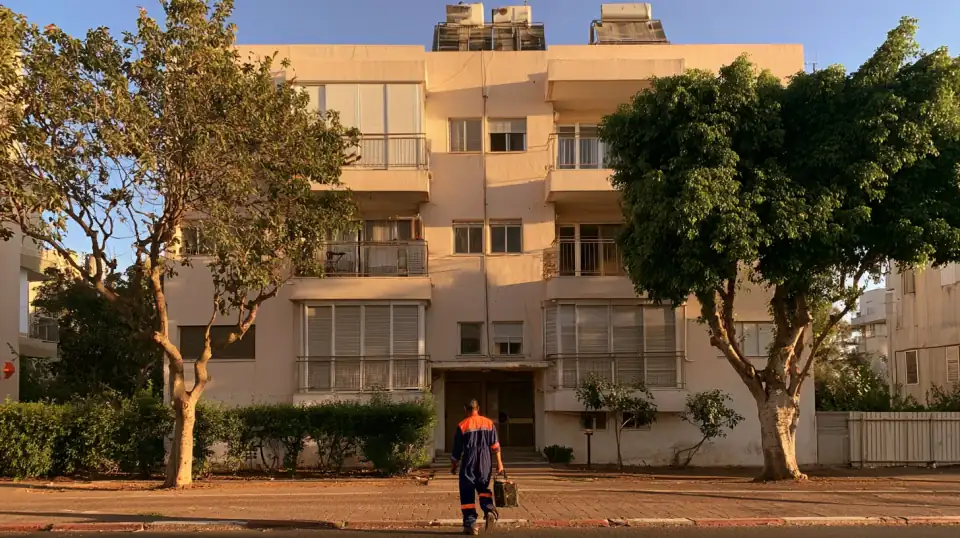 אינסטלטור עם ארגז כלים בדרך לבניין מגורים ותיק