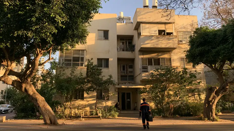 אינסטלטור עם ארגז כלים בדרך לבניין מגורים ותיק