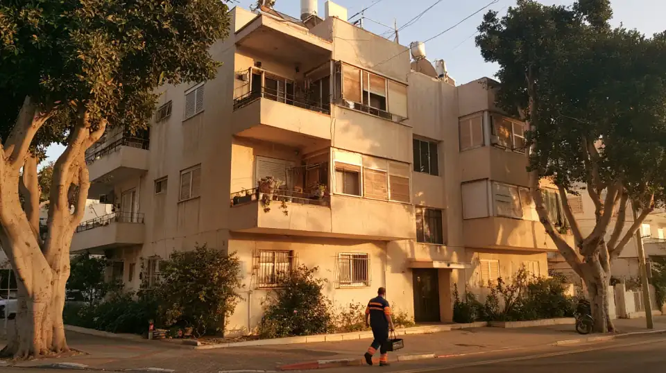 אינסטלטור עם ארגז כלים בדרך לבניין מגורים ותיק